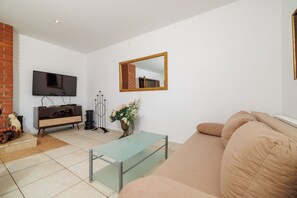 A living room with a television, sofa, coffee table, and a mirror on the wall. - Apartments Andrijanic (Crikvenica)