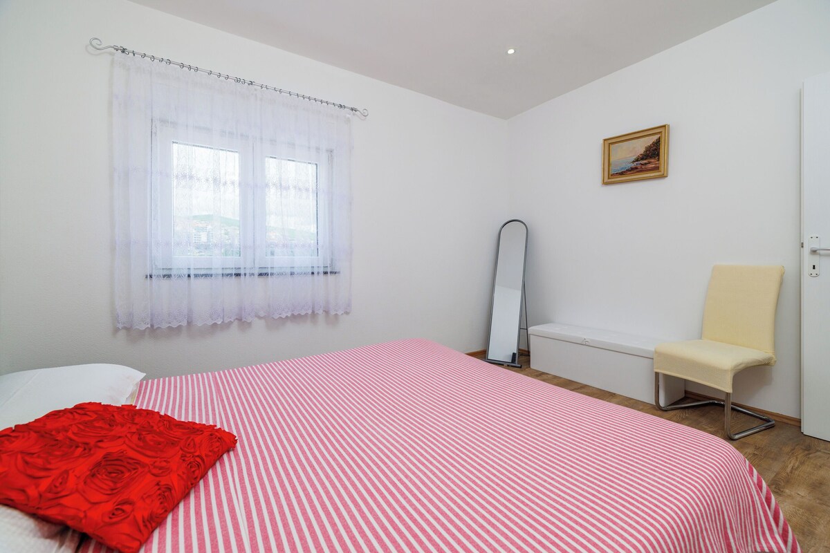 Ein Schlafzimmer mit Bett, Sessel, Spiegel und einem Bild an der Wand.