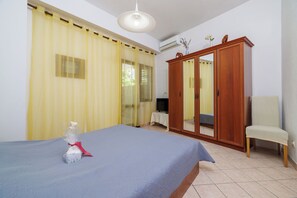 A bedroom with a bed, a wardrobe, a chair, and a television. - Apartments Andrijanic (Crikvenica)