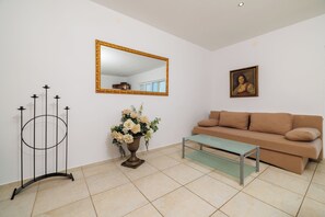 A living room with a sofa, a glass coffee table, a mirror, a flower vase, and a candle holder. - Apartments Andrijanic (Crikvenica)