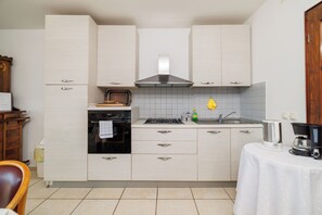 A kitchen with white cabinets, a stove, oven, and a sink. - Apartments Andrijanic (Crikvenica)