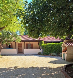 A building with a red-tiled roof, a gravel driveway, and a tree in the foreground. - Apartments Laura and Romano With Pool (Vir)