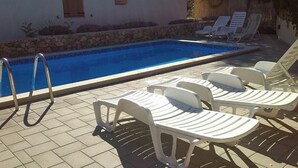 Une piscine avec des chaises longues et un mur en pierre.