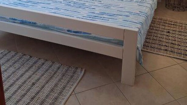 Une chambre à coucher avec un lit, deux lampes de chevet, un tapis et un tableau accroché au mur.