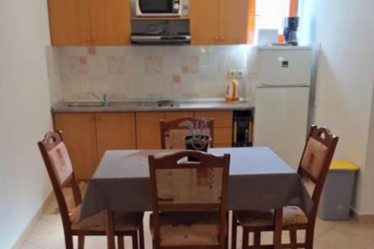 A kitchen with wooden cabinets, a microwave, a sink, and a dining table with chairs.