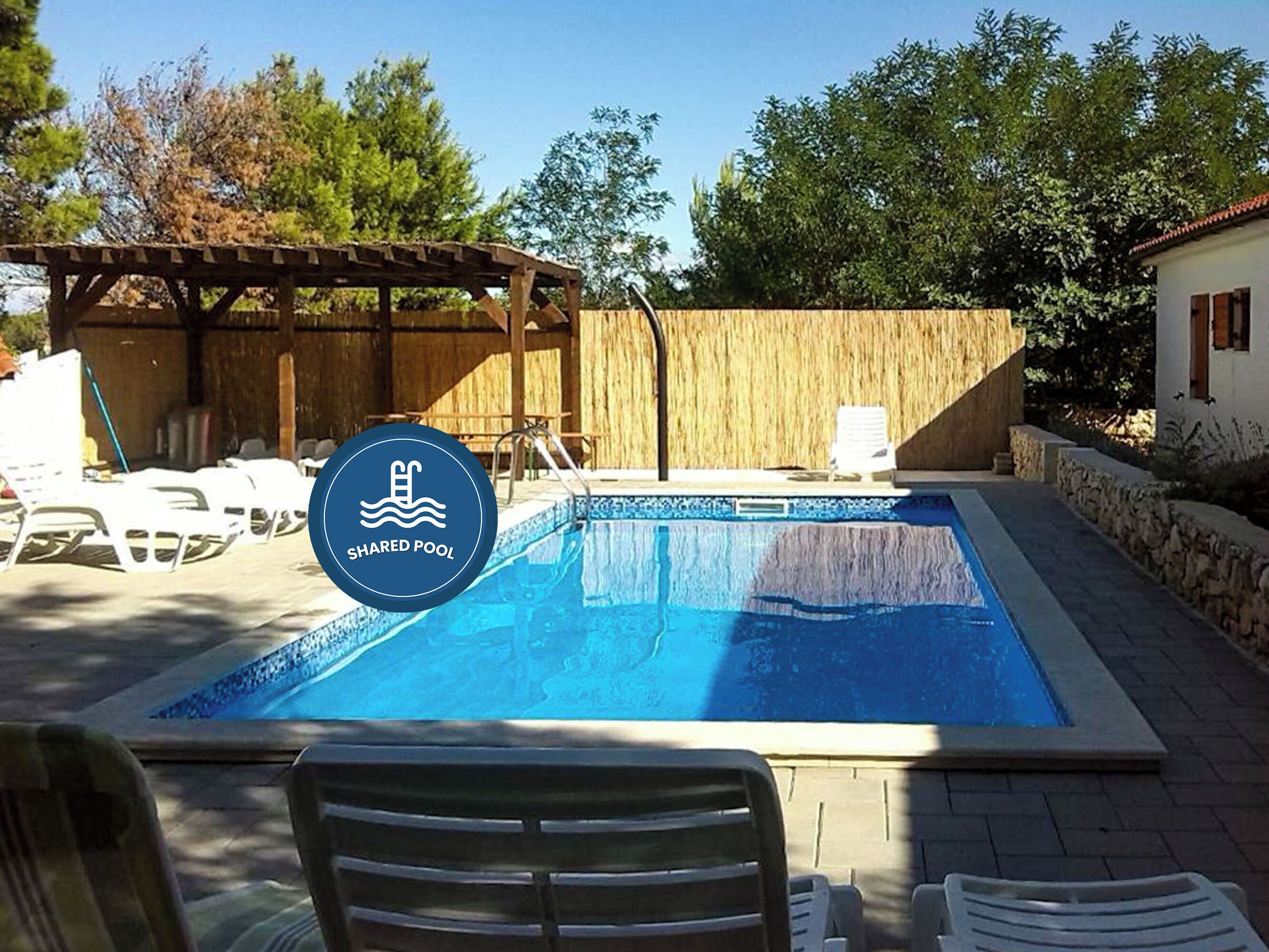 Una piscina rectangular con un muelle de madera y sillas de descanso.