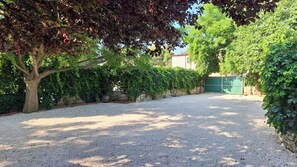 A gravel driveway leading to a gated entrance, surrounded by dense greenery and trees. - Apartments Laura and Romano With Pool (Vir)