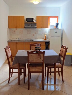 A small kitchen with wooden cabinets, a microwave, a sink, and a refrigerator. - Apartments Laura and Romano With Pool (Vir)