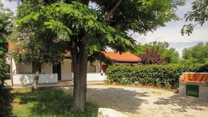 Un espace extérieur verdoyant avec un arbre, un objet blanc et un bâtiment doté d’un toit rouge.
