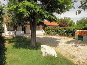 A grassy outdoor area with a tree, a white object, and a building with a red roof. - Apartments Laura and Romano With Pool (Vir)