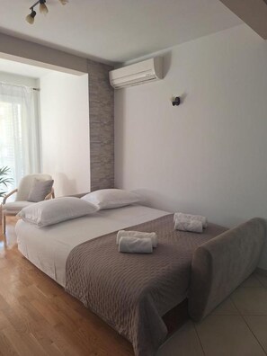 A modern hotel room with a large bed, a chair, and an air conditioning unit. - Apartment Goran (Makarska)