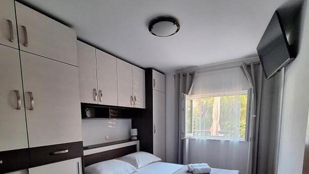 A bedroom with a bed, a TV, and a window. - Apartment Goran (Makarska)