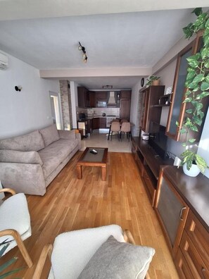 A living room with a sofa, a coffee table, and a TV stand. - Apartment Goran (Makarska)