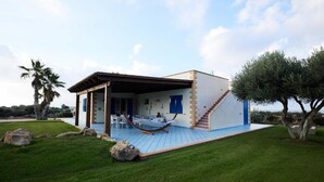 Ein modernes Haus mit überdachter Terrasse, einer Hängematte und einer Treppe zum oberen Stockwerk.