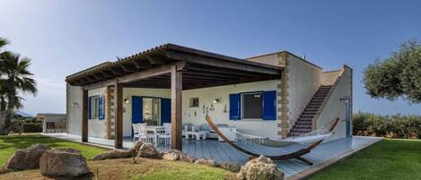 Uma casa moderna com varanda coberta, área de estar externa e uma rede.