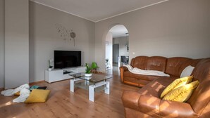 A living room with a brown leather sofa, a glass coffee table, a flat-screen TV, and a white entertainment unit. - House Villa Lara (Marcana)