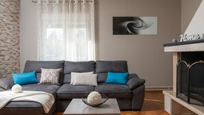 A living room with a grey sofa, a white coffee table, and a fireplace. - House Villa Lara (Marcana)