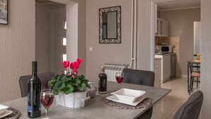 A dining area with a table set for two, a potted plant, wine bottles, and glasses. - House Villa Lara (Marcana)