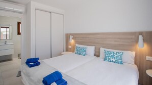 A hotel room with a large bed, two bedside lamps, a wooden headboard, and a mirror above the sink. - Villa Montane 10 - Three Bedroom Villa, Sleeps 6 (Playa Blanca)