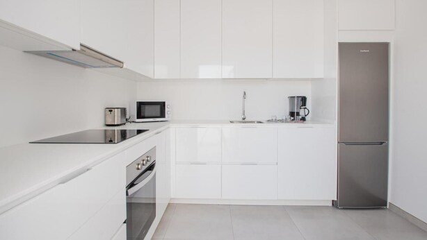 A modern kitchen with white cabinetry, a stainless steel refrigerator, a microwave, a toaster, and a coffee maker. - Villa Montane 10 - Three Bedroom Villa, Sleeps 6 (Playa Blanca)