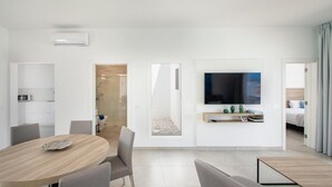 A modern hotel room with a dining area, a TV, and a shower. - Villa Montane 10 - Three Bedroom Villa, Sleeps 6 (Playa Blanca)