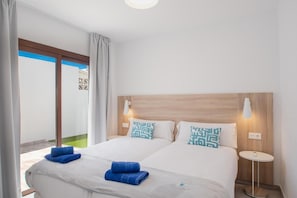 A hotel room with a double bed, two pillows, a bedside table with a lamp, and a view of a balcony. - Villa Montane 10 - Three Bedroom Villa, Sleeps 6 (Playa Blanca)