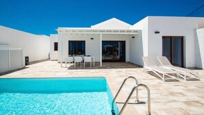 A pool area with a clear blue pool, a covered seating area with tables and chairs, and sun loungers. - Villa Montane 10 - Three Bedroom Villa, Sleeps 6 (Playa Blanca)