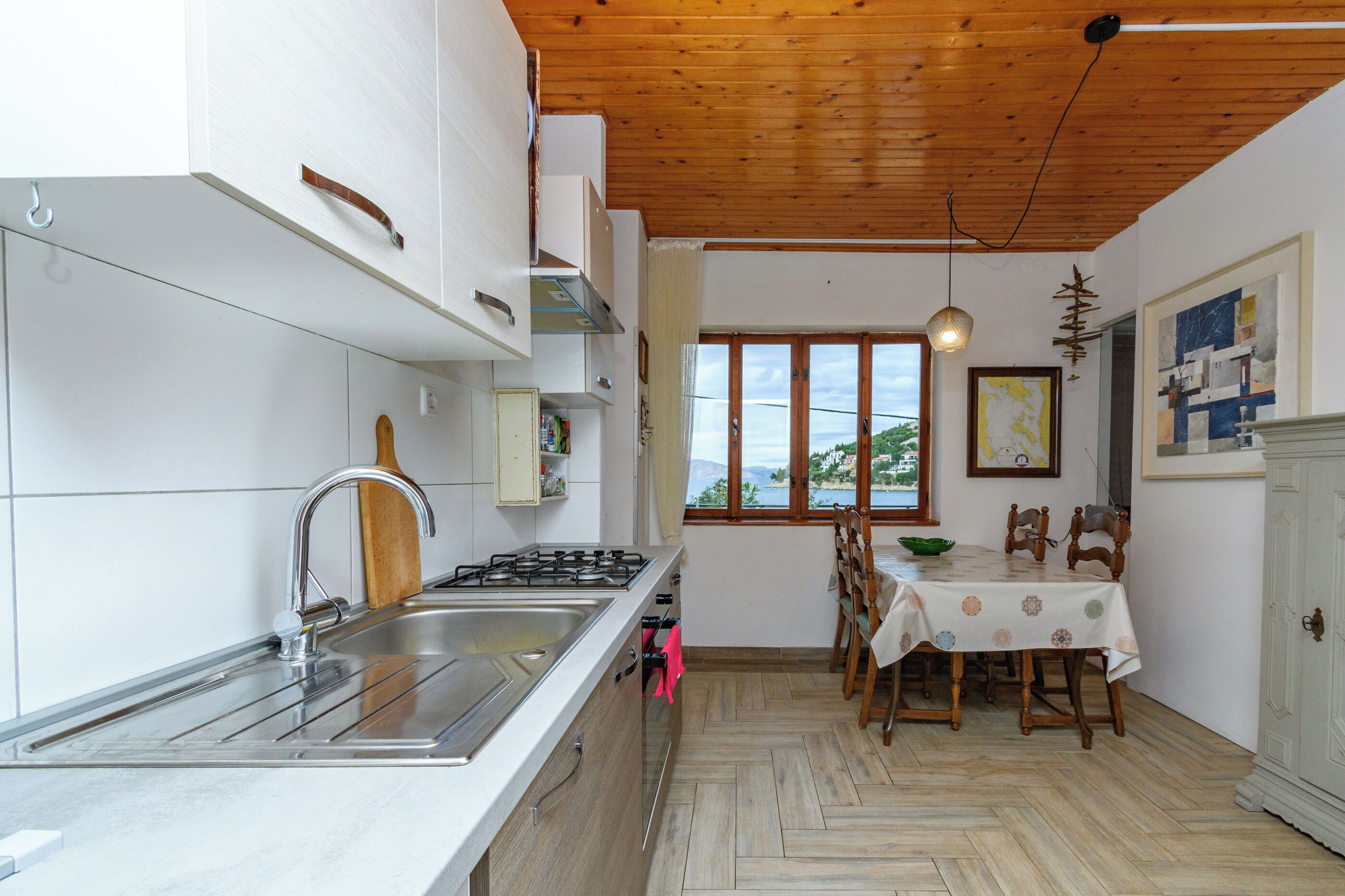 A kitchen with a sink, stove, and dining area with a table and chairs.