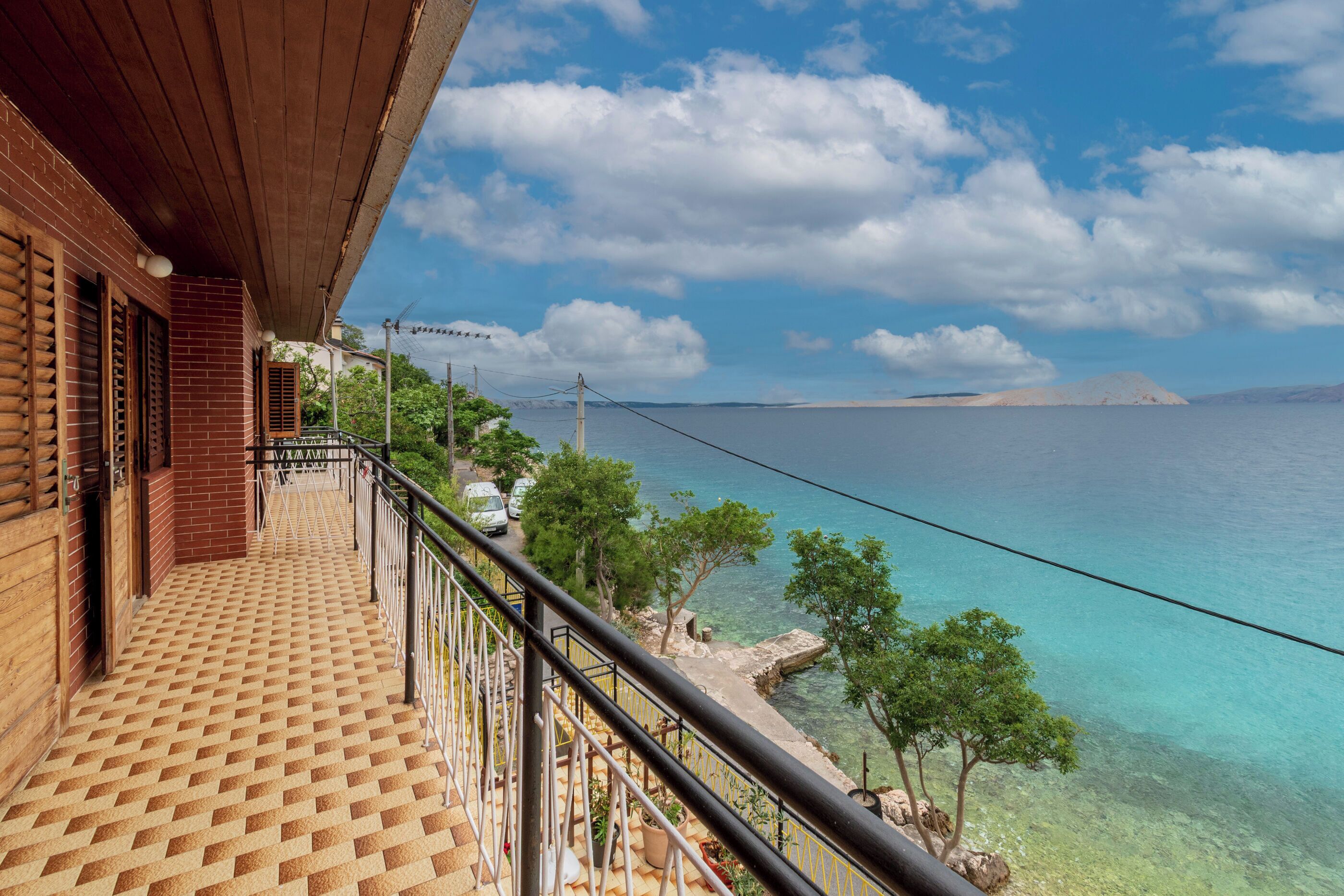 Un balcone con pavimento decorato, vista sul mare e cielo sereno.