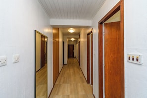 Ein schmaler Flur mit Holztüren und einer Leuchte an der Decke.