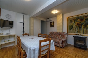 Ein Essbereich mit Tisch, Stühlen, Fernseher, einer Couch, einem Gemälde und einem Kamin.