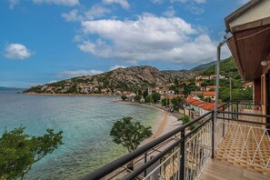 Eine Küstenstadt mit freiem Blick auf das Meer, ein Berg im Hintergrund und ein Balkon mit Geländer.