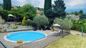 A swimming pool with a stone wall, surrounded by greenery and tall trees. - "A Provençal Getaway for Two in Haute-Provence" (Revest-Saint-Martin)