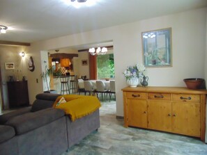 Ein Wohnzimmer mit einer Couch, einem Holzschrank und einem Essbereich mit Stühlen und einem Tisch.