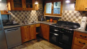 A kitchen with wooden cabinets, a black stove, and a dishwasher. - "A Provençal Getaway for Two in Haute-Provence" (Revest-Saint-Martin)