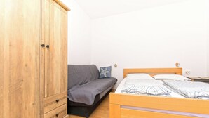 Ein Schlafzimmer mit einem Holzkleiderschrank, einer Couch und einem Bett.