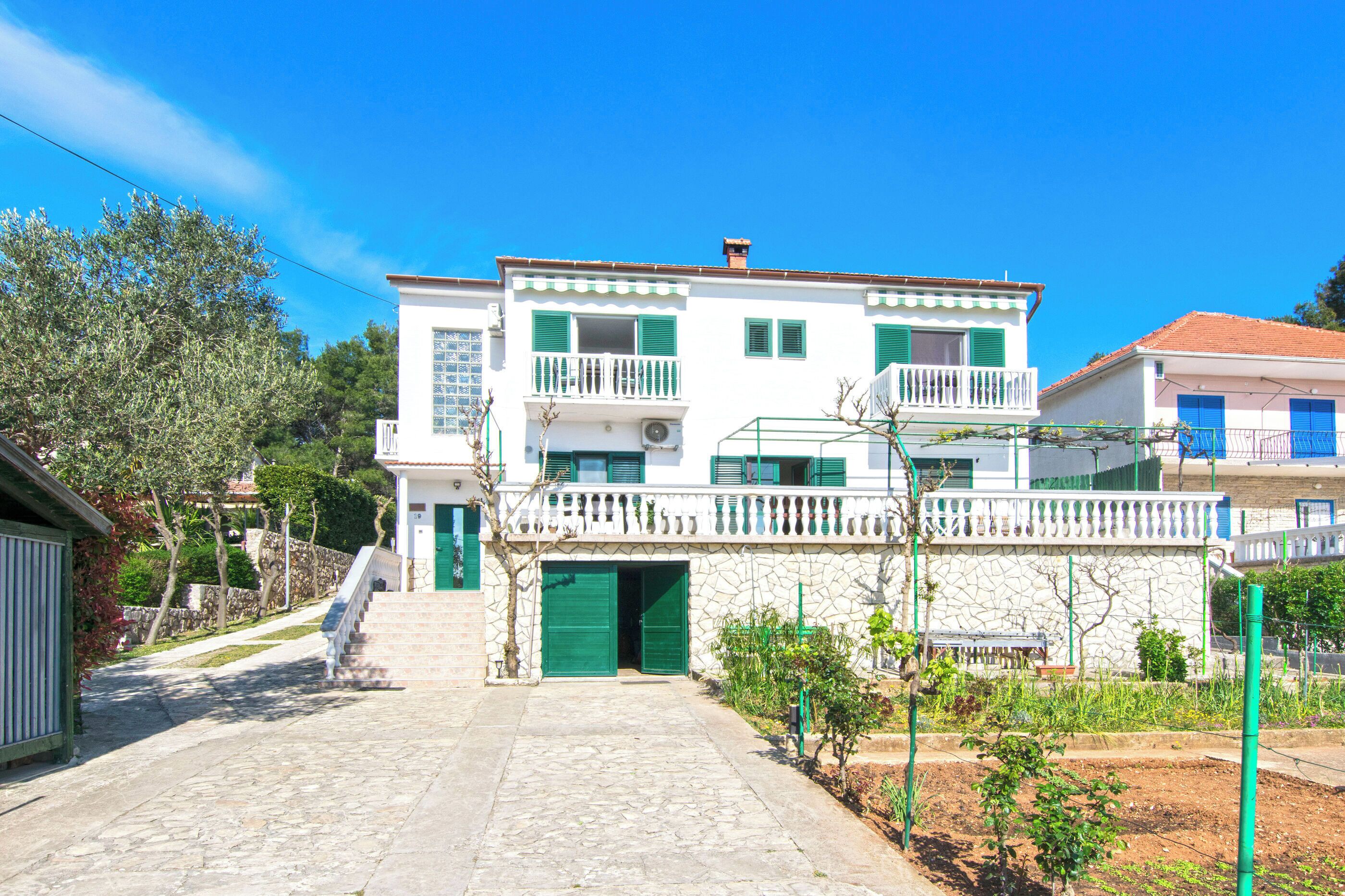 A two-story building with a stone facade, green shutters, and a balcony.