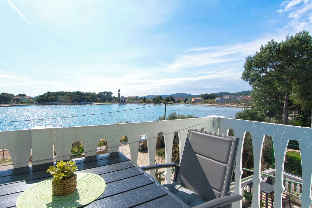 Ein Balkon mit Blick auf einen Fluss, einem Stuhl und einer kleinen Pflanze.