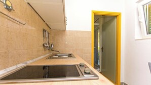 Eine Küche mit integriertem Spülbecken, einem Herd und einem Fenster mit gelbem Rahmen.