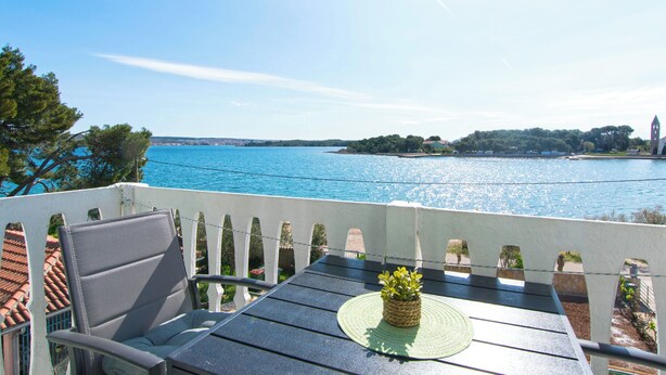 Ein Balkon mit Tisch, Stühlen und Blick auf ein Gewässer.