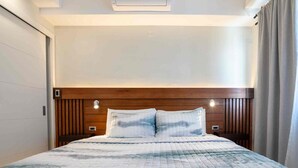 A hotel room with a large bed, wooden headboard, and a view of the sea. - VIA Braemar Suites - with roof-top pool (Kingston)