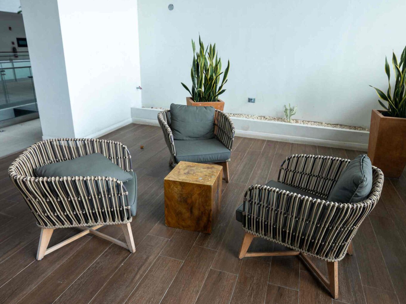 Uma área de estar moderna com móveis de vime, uma mesa de centro de madeira e plantas em vasos.