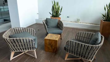 Uma área de estar moderna com móveis de vime, uma mesa de centro de madeira e plantas em vasos.
