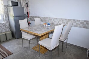 A kitchen with a dining table, chairs, a refrigerator, and a microwave. - Apartments Plavsic (Novi Vinodolski)