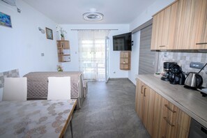 A modern kitchen with wooden cabinets, a built-in oven, and a coffee maker. - Apartments Plavsic (Novi Vinodolski)