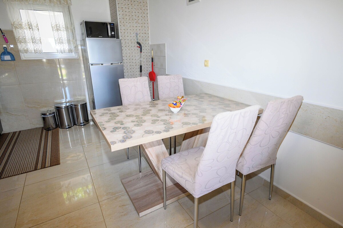 A kitchen with a dining table, chairs, a microwave, and a refrigerator.