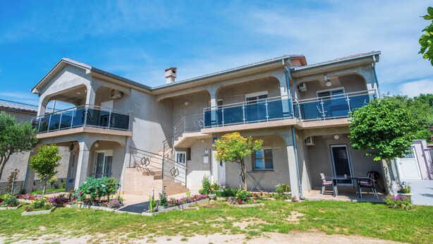 A two-story building with a balcony, a staircase, and a small garden area. - Apartments Plavsic (Novi Vinodolski)