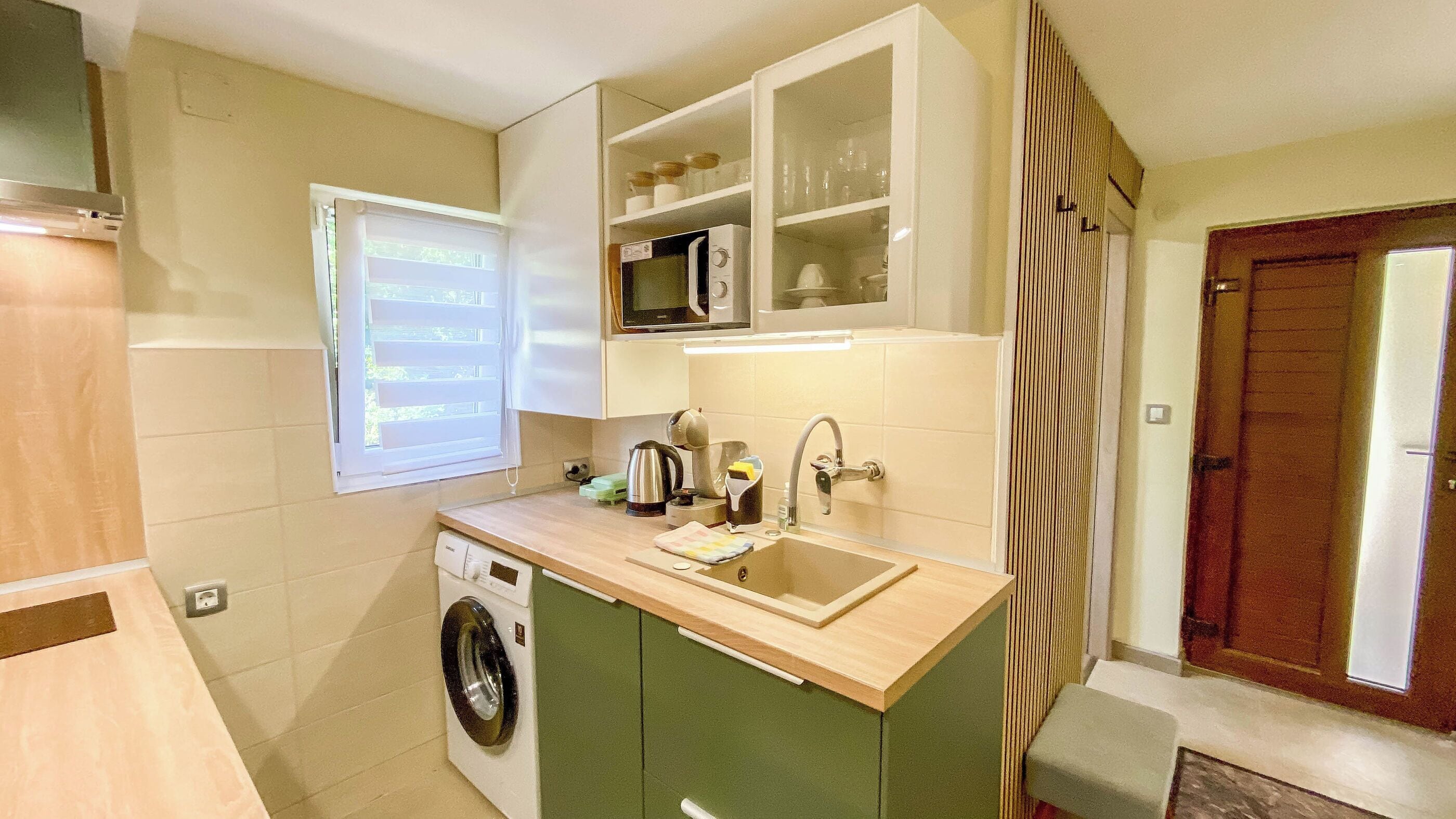 A compact kitchen with a washing machine, a microwave, and a sink.