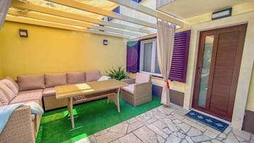 A patio with a sofa, table, and chairs, a small plant, and a door with a window.