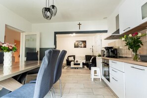 A modern kitchen with white cabinets, a dining area with a table and chairs, and a living room with a sofa and coffee table. - House Bistre With Private Pool (Razanac)
